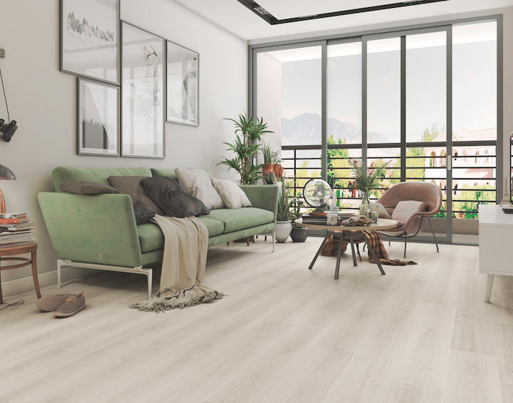 Ein hell eingerichtetes Wohnzimmer mit grünem Sofa und Holzoptikboden