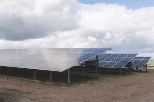 Mehrere Solarpanels stehen auf einem Feld unter wolkigem Himmel