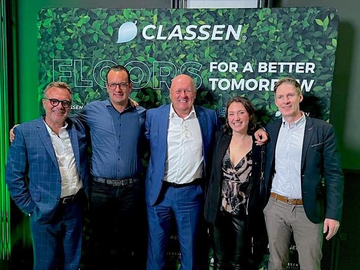 Gruppenfoto von fünf Personen vor einer CLASSEN Messewand mit dem Slogan ‚Floors for a better tomorrow‘ – Symbol für Teamgeist, Nachhaltigkeit und die Zukunft umweltfreundlicher Bodenbeläge