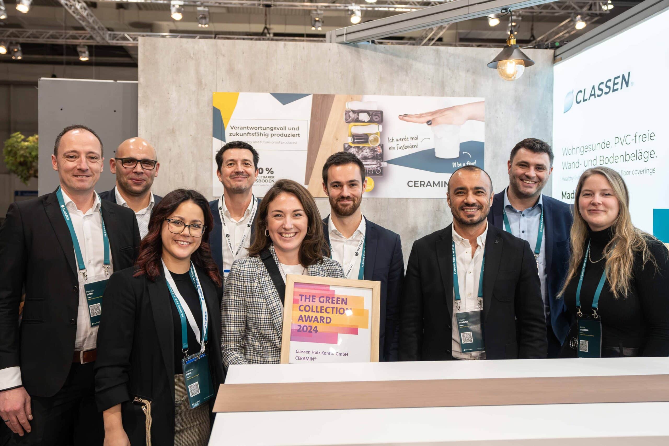 Gruppenfoto des CLASSEN Teams auf einer Fachmesse mit Urkunde des The Green Collection Award 2024 für nachhaltige, PVC-freie Bodenbeläge – Symbol für Innovation, Umweltbewusstsein und erfolgreiche Produktentwicklung.